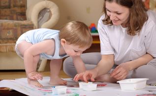 Kvinde og lille barn maler med fingermaling